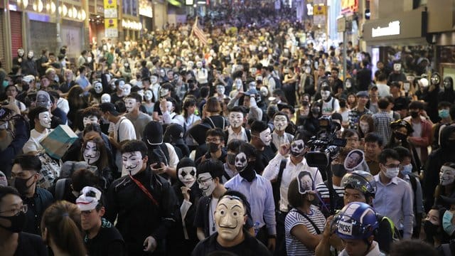 Maskierte Demonstranten versammeln sich auf einer Straße in Hongkong. Maskierte Demonstranten versammeln sich auf einer Straße in Hongkong.