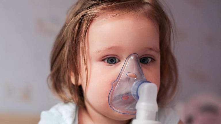 Kleinkind mit Atemgerät: Um die Atmung zu erleichtern, können Sie das Kind auch mit einer Kochsalzlösung inhalieren lassen.