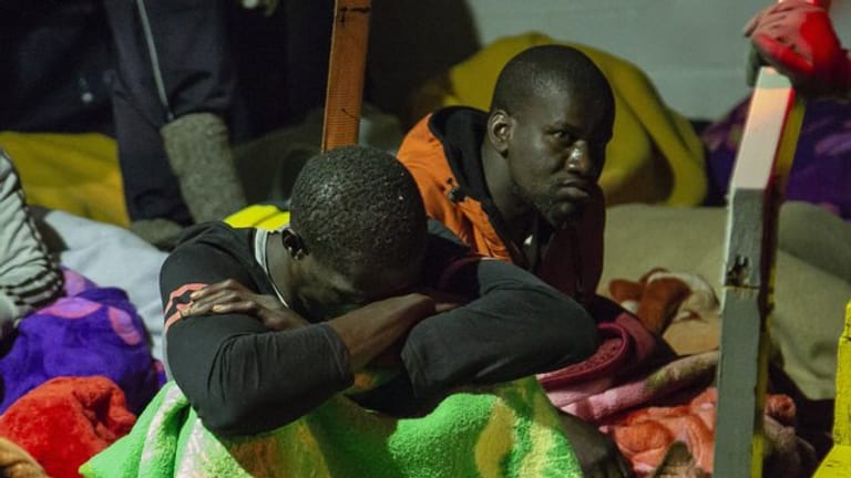 Migranten sitzen an Deck des unter deutscher Flagge fahrenden Schiffes "Alan Kurdi".