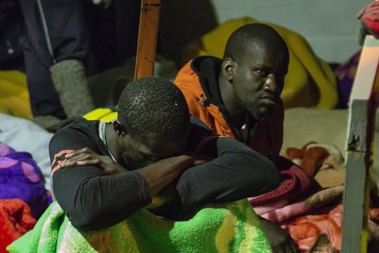 Migranten sitzen an Deck des unter deutscher Flagge fahrenden Schiffes "Alan Kurdi".