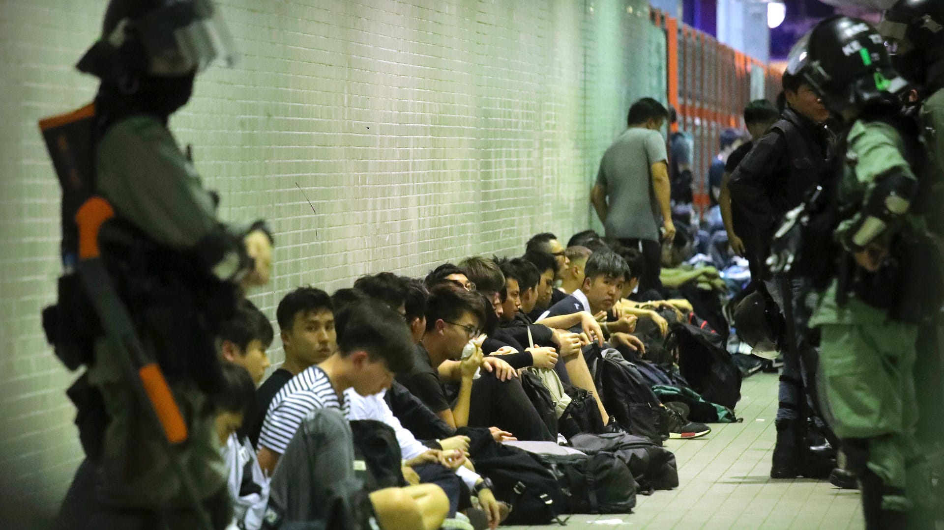 Polizisten in Hongkong bewachen festgenommene Demonstranten: Die Aktivisten setzten sich immer wieder über Versammlungsverbote hinweg.