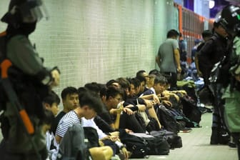 Polizisten in Hongkong bewachen festgenommene Demonstranten: Die Aktivisten setzten sich immer wieder über Versammlungsverbote hinweg.