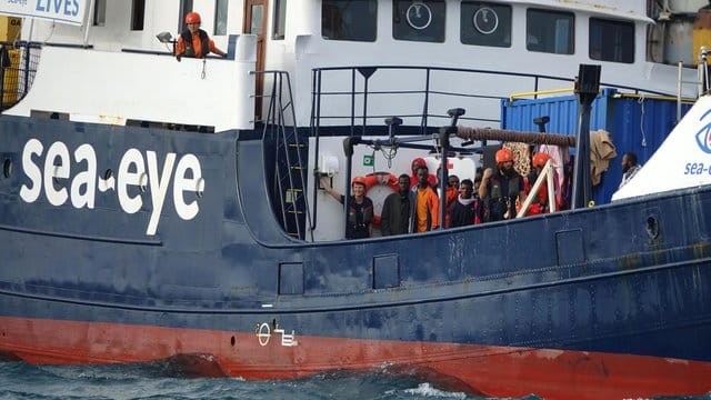 Migranten und Besatzungsmitglieder stehen an Deck des deutschen Rettungsschiffs "Alan Kurdi". Migranten und Besatzungsmitglieder stehen an Deck des deutschen Rettungsschiffs "Alan Kurdi".