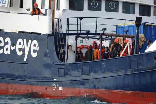 Migranten und Besatzungsmitglieder stehen an Deck des deutschen Rettungsschiffs "Alan Kurdi".