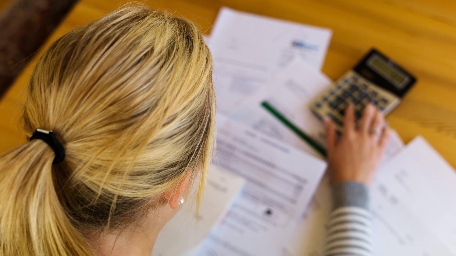 Eine Frau sitzt über Briefen: 424 Euro im Monat beziehen alleinstehende Hartz-IV-Empfänger momentan – es sei denn, sie verstoßen gegen Auflagen. (Symbolbild)