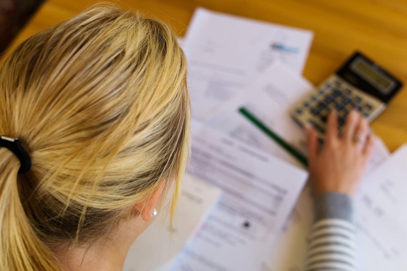 Eine Frau sitzt über Briefen: 424 Euro im Monat beziehen alleinstehende Hartz-IV-Empfänger momentan – es sei denn, sie verstoßen gegen Auflagen. (Symbolbild)