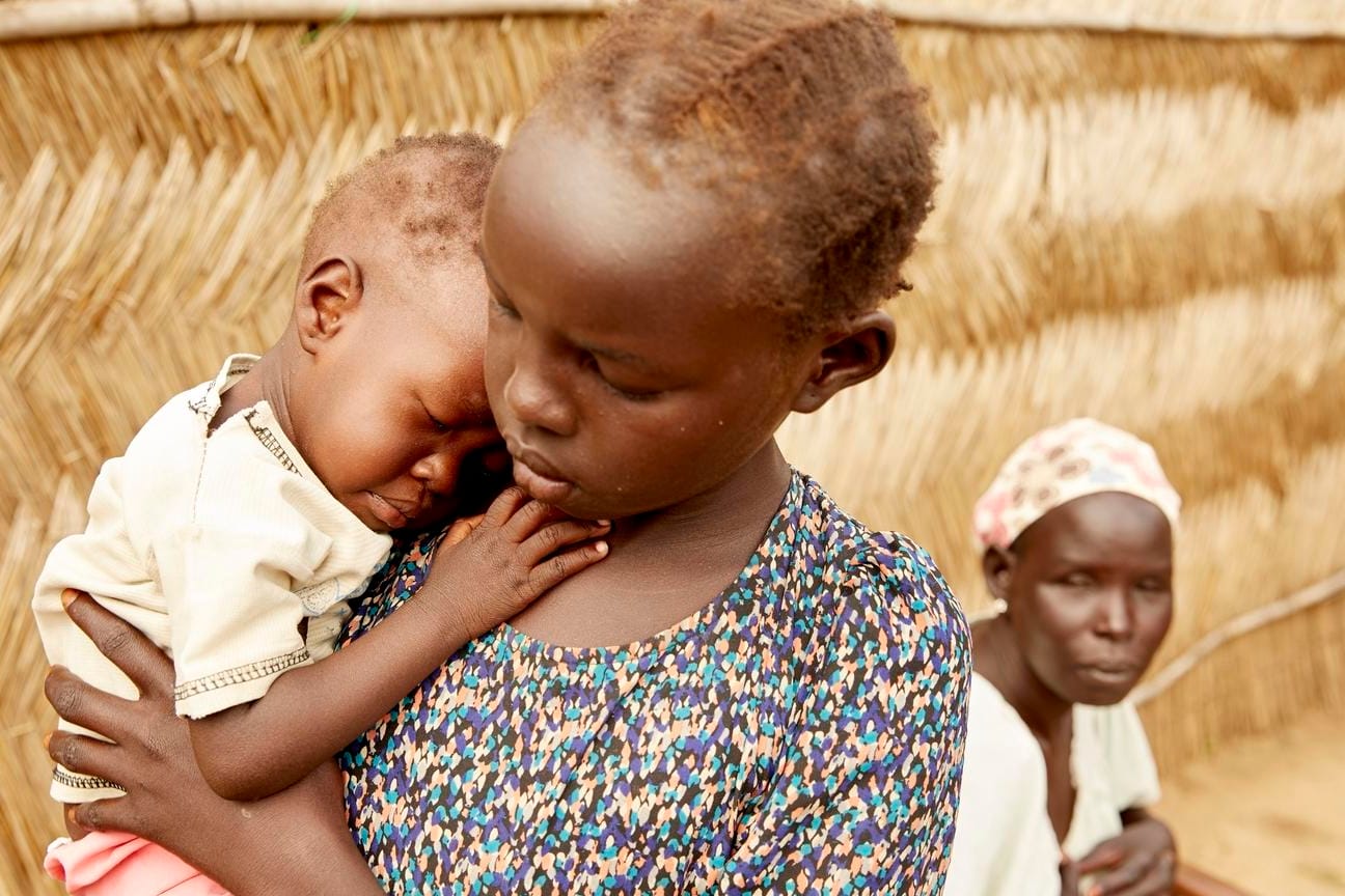 Adut (14 Monate) aus dem Südsudan auf dem Arm ihrer großen Schwester Lydia. Adut ist lebensbedrohlich mangelernährt.