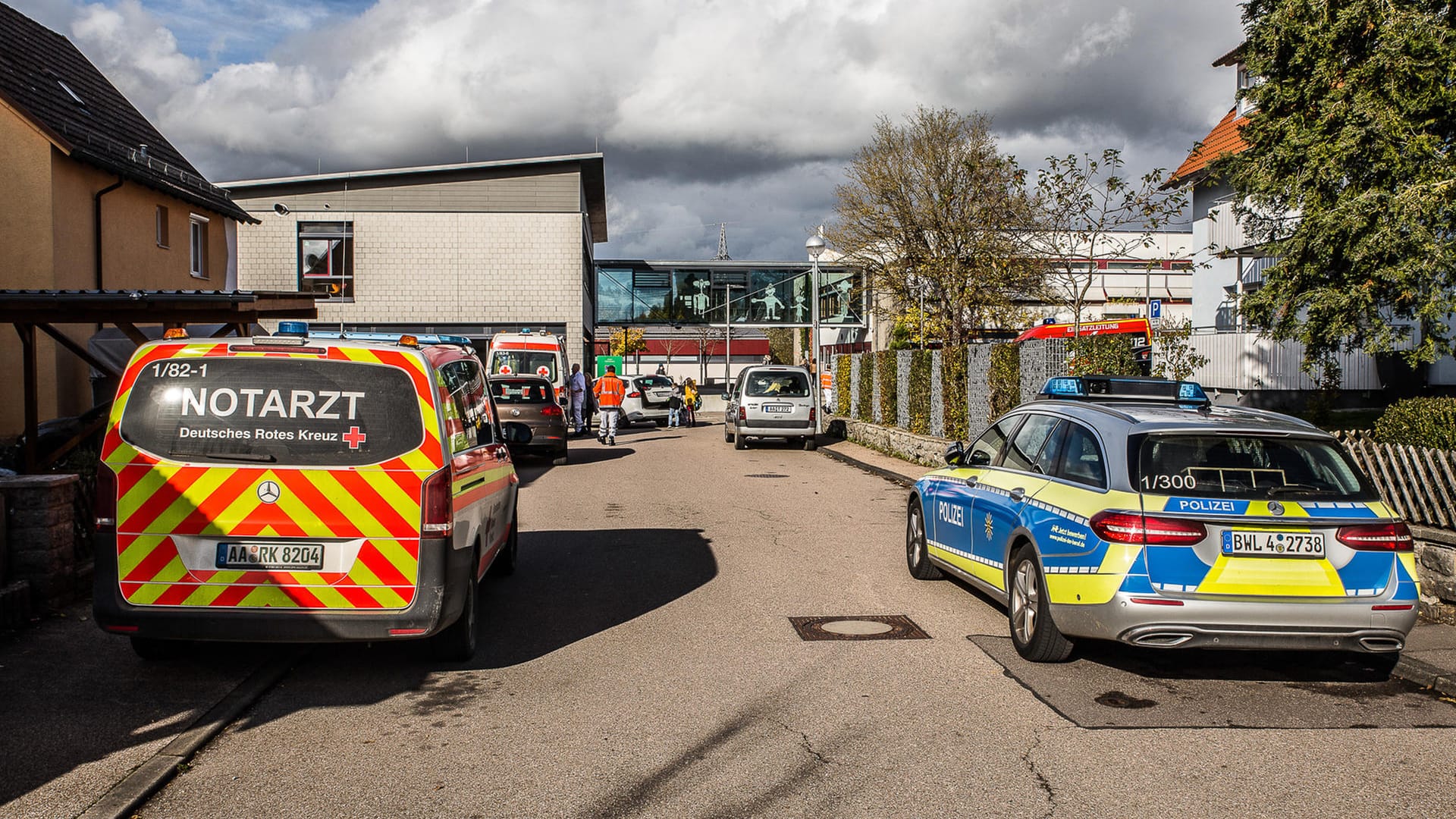 Einsatzkräfte der Rettungsdienste stehen vor der betroffenen Schule: Die Lehrerin musste nach dem Vorfall in ein Krankenhaus.