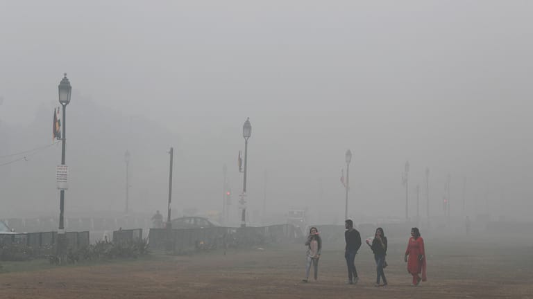 Passanten auf einem Bürgersteig in Neu-Delhi. Doch, genau das zeigt dieses Bild (und natürlich viel Smog).