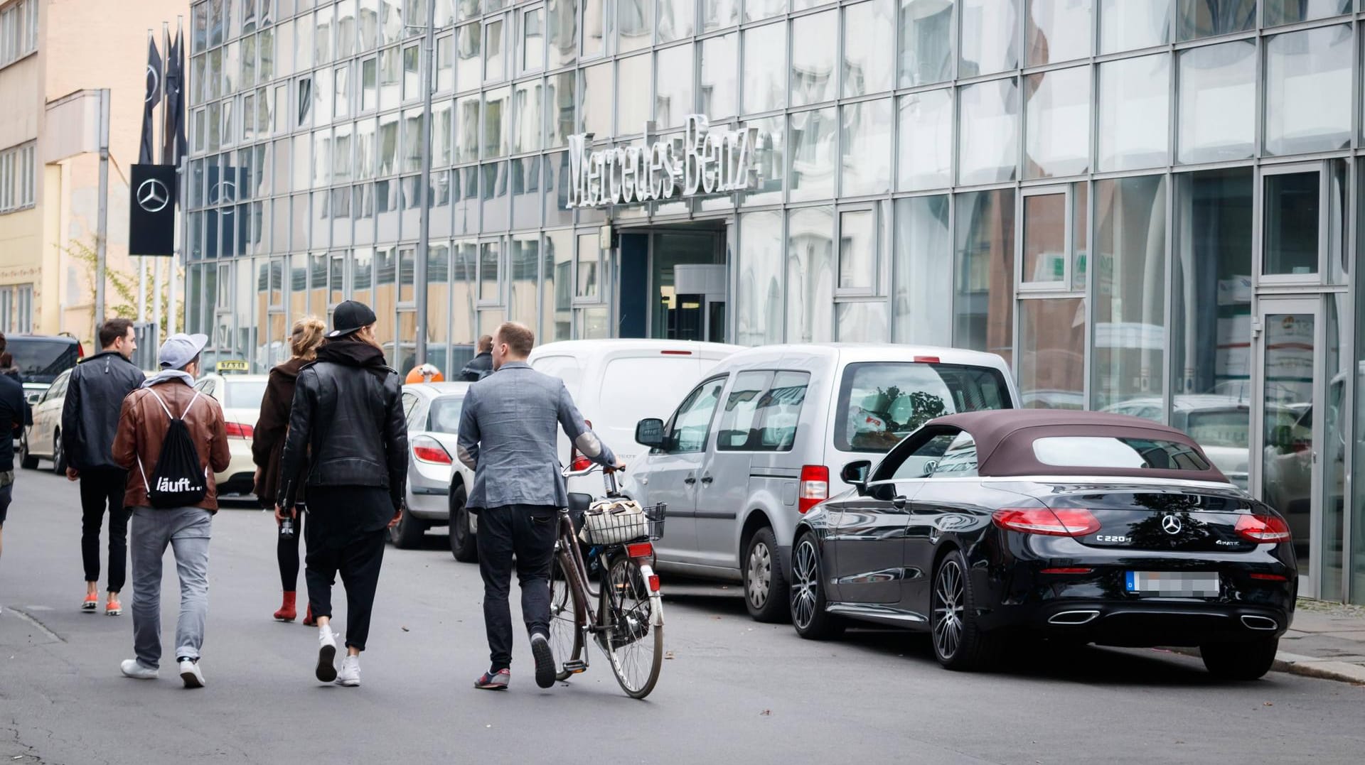 Passanten laufen an dem Autohaus vorbei, das nun angegriffen wurde: Mehrere Zeugen beobachten den Übergriff, doch die Täter waren vermummt. (Archivbild)