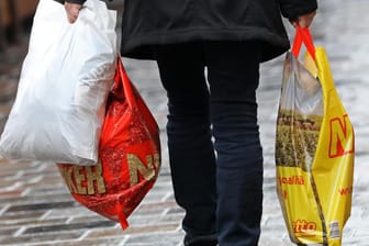 Eine Frau trägt drei Einkaufstüten: An Deutschlands Ladenkassen sollen Einwegtragetaschen aus Kunststoff verboten werden.