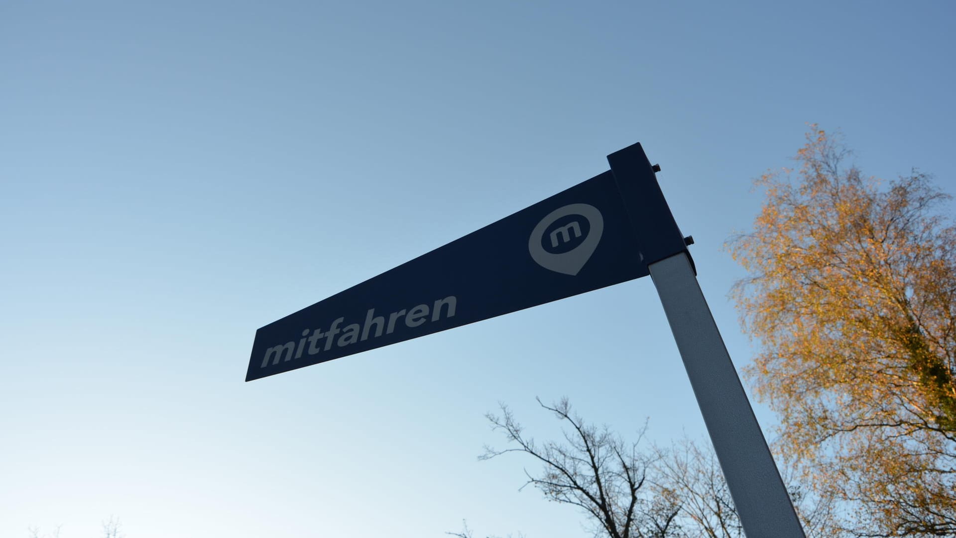 Schild mit der Aufschrift "mitfahren": Hier können sich Menschen versammeln, die zu einem der nahe gelegenen Ziele gebracht werden wollen.