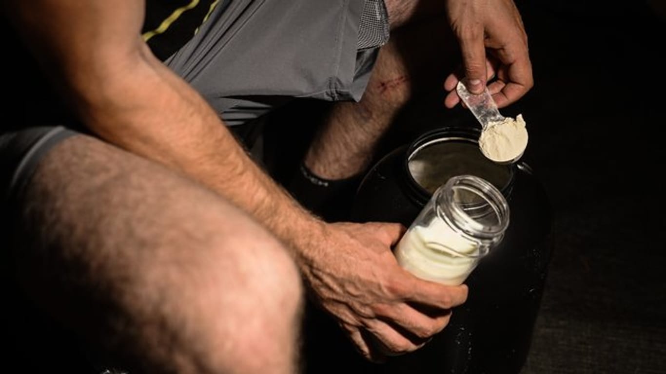 Ein Mann mischt sich nach dem Training Proteinpulver in seinen Shaker.