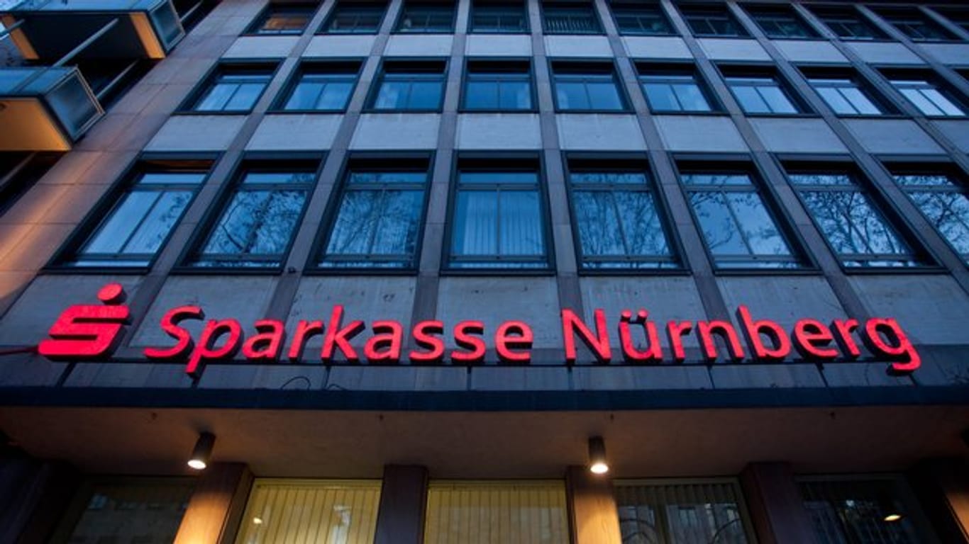 Das beleuchtete Logo einer Sparkasse in Nürnberg (Archivbild): Kunden wehren sich gegen Vertragskündigungen.