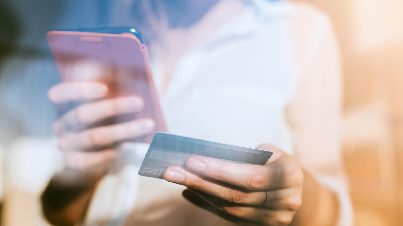 Eine Frau tippt ihre Kreditkartendaten in ein Smartphone ein: In der Vorweihnachtszeit locken viele Online-Händler mit Sonderangeboten zum Singles Day oder Black Friday.