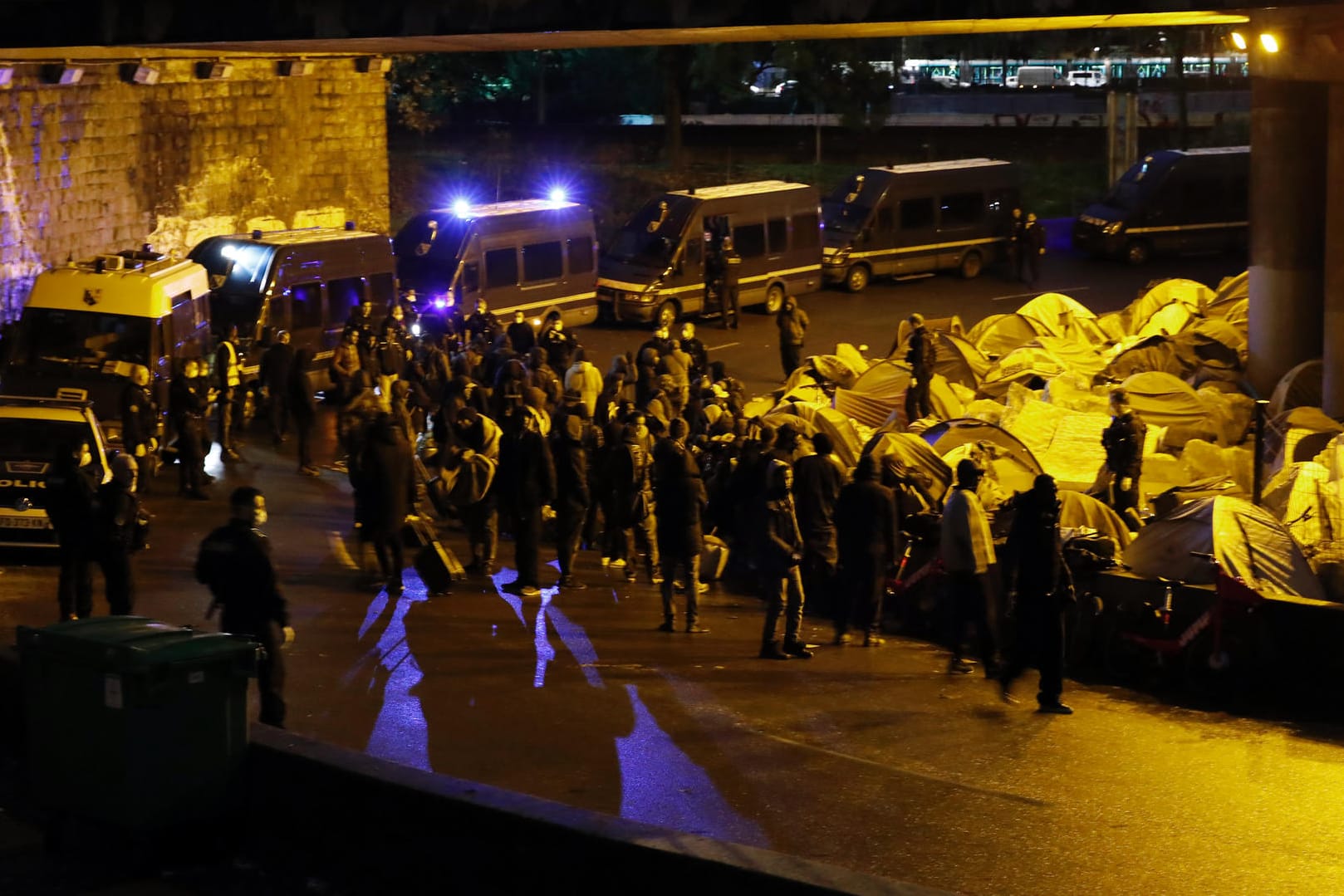 Französische Polizisten und Gendarmen kontrollieren Migranten während der Räumung eines provisorischen Flüchtlingscamps: In einem Camp im Pariser Vorort Saint-Denis waren Hunderte Polizisten vor Ort.