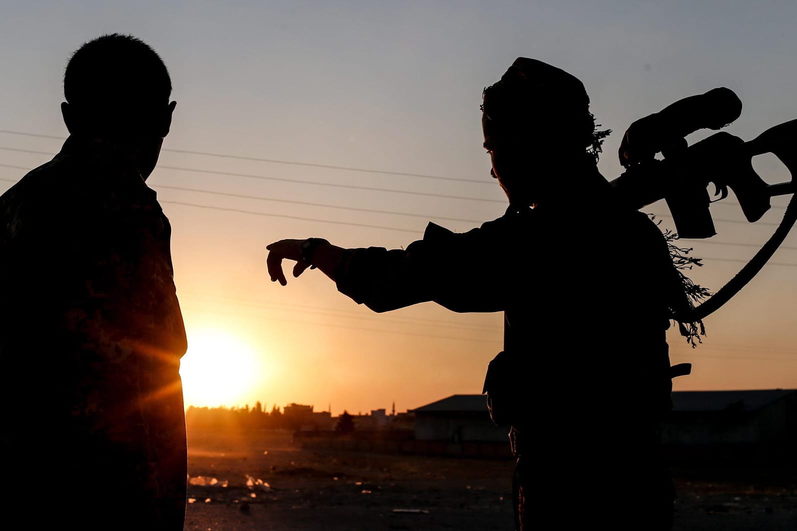 Mitglieder der Kurdischen Volksverteidigungseinheiten (YPG) stehen Wache im Sonnenuntergang: Die deutschen Kämpfer in Syrien müssen mit rechtlichen Konsequenzen in Deutschland rechnen.