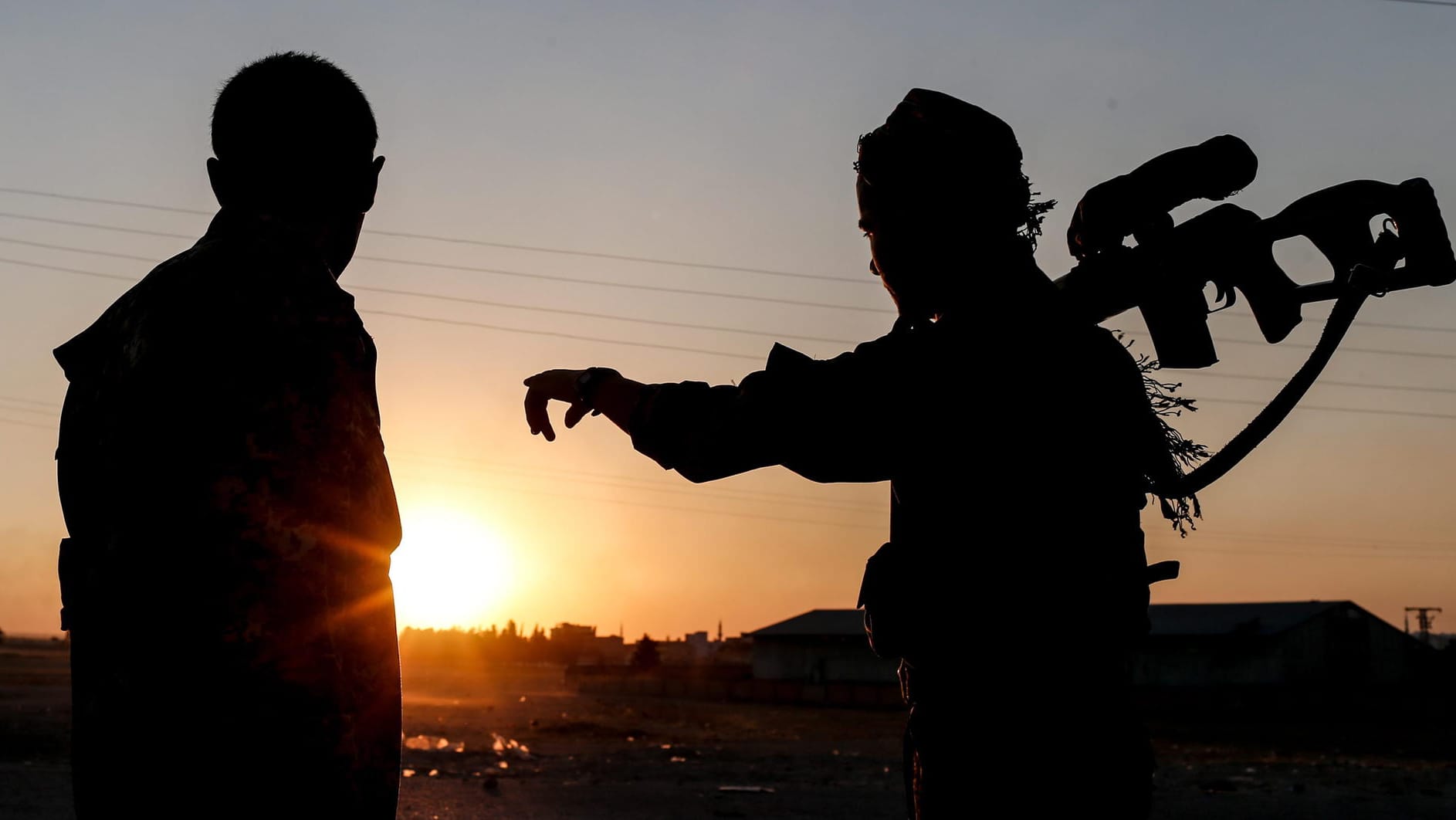 Mitglieder der Kurdischen Volksverteidigungseinheiten (YPG) stehen Wache im Sonnenuntergang: Die deutschen Kämpfer in Syrien müssen mit rechtlichen Konsequenzen in Deutschland rechnen.