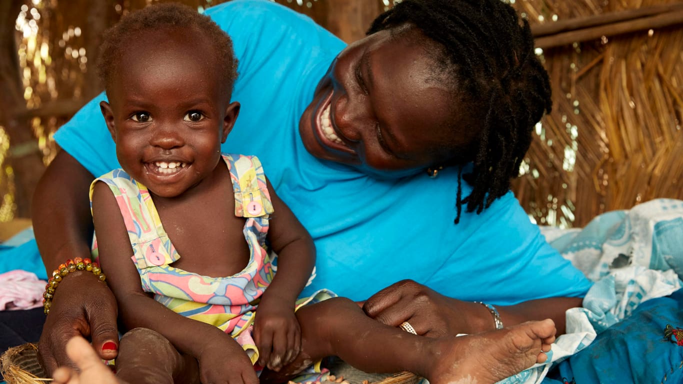 Nothelferin Jesca Wude Murye besucht Adut aus dem Südsudan zu Hause: Nach acht Wochen Behandlung hat sich das zuvor schwer mangelernährte Mädchen vollständig erholt.