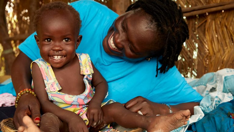 Nothelferin Jesca Wude Murye besucht Adut aus dem Südsudan zu Hause: Nach acht Wochen Behandlung hat sich das zuvor schwer mangelernährte Mädchen vollständig erholt.