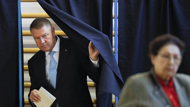 Klaus Iohannis, Präsident von Rumänien, verlässt eine Wahlkabine mit einem Stimmzettel.