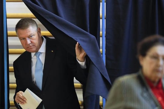 Klaus Iohannis, Präsident von Rumänien, verlässt eine Wahlkabine mit einem Stimmzettel.