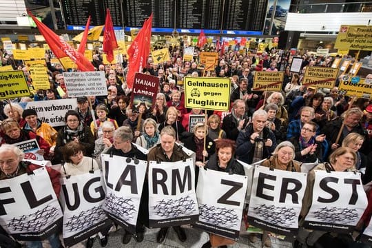 Kundgebungsteilnehmer stehen mit Plakaten im Terminal