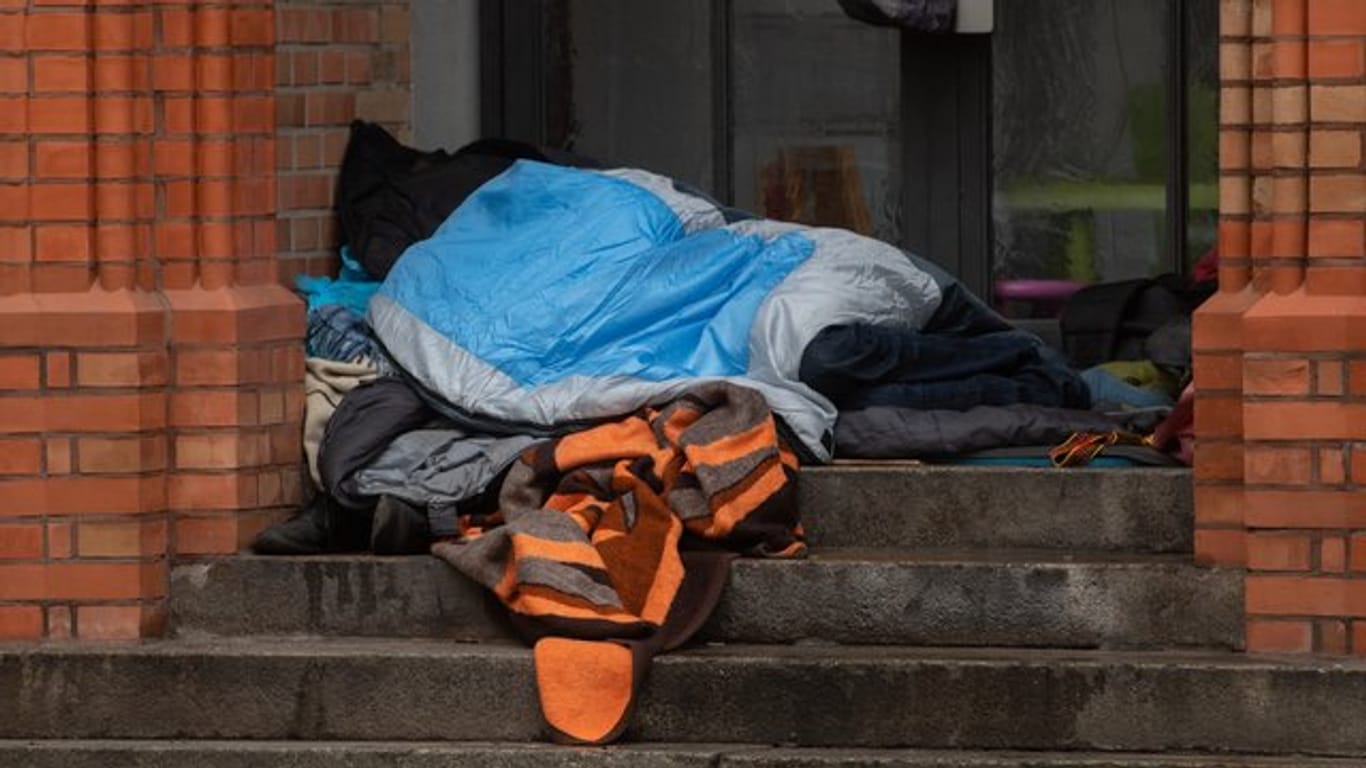 Ein Obdachloser liegt in einem Eingang einer Kirche in Berlin.