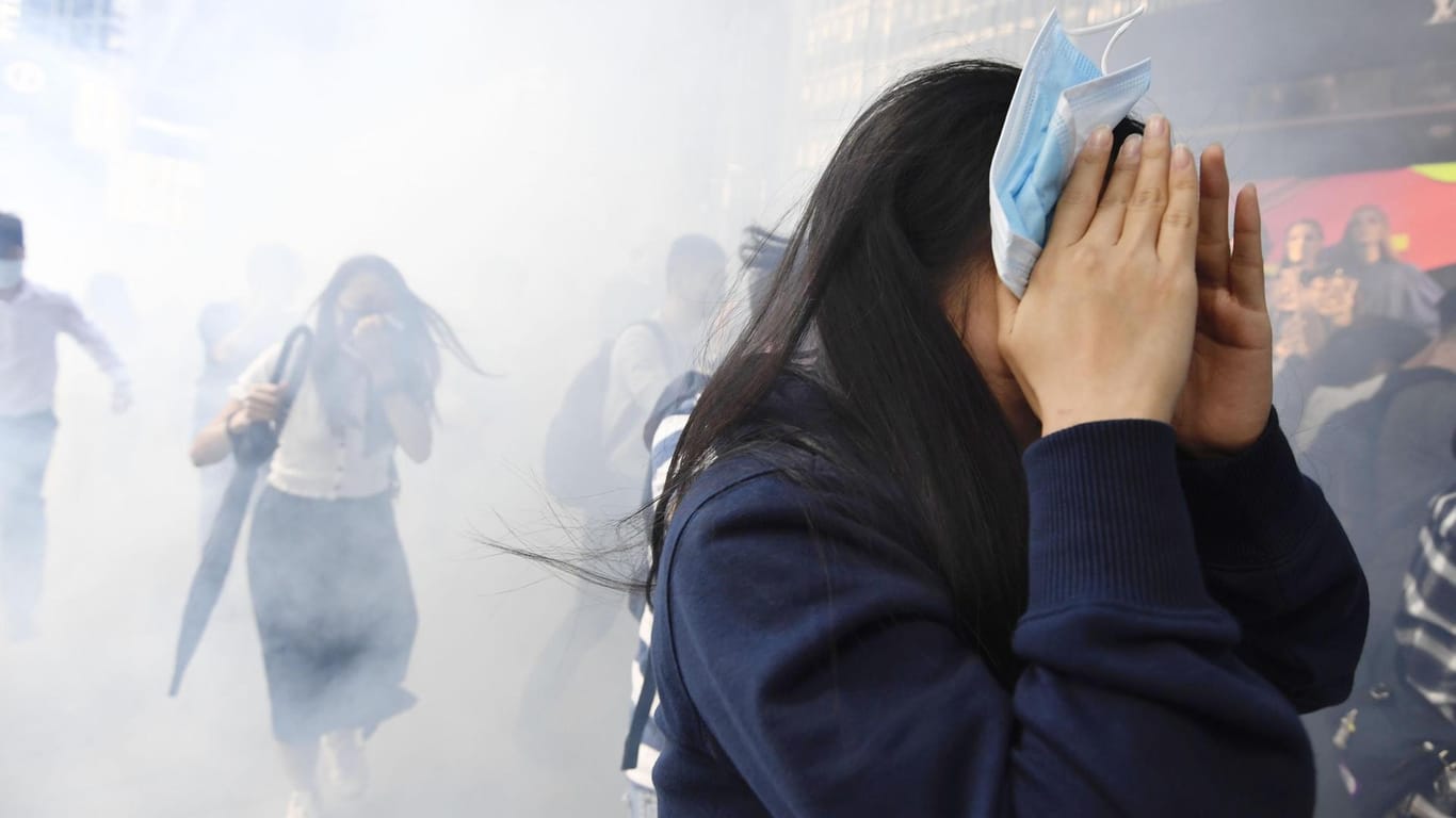 Demonstranten versuchen sich vor dem Tränengas der Polizei zu schützen.