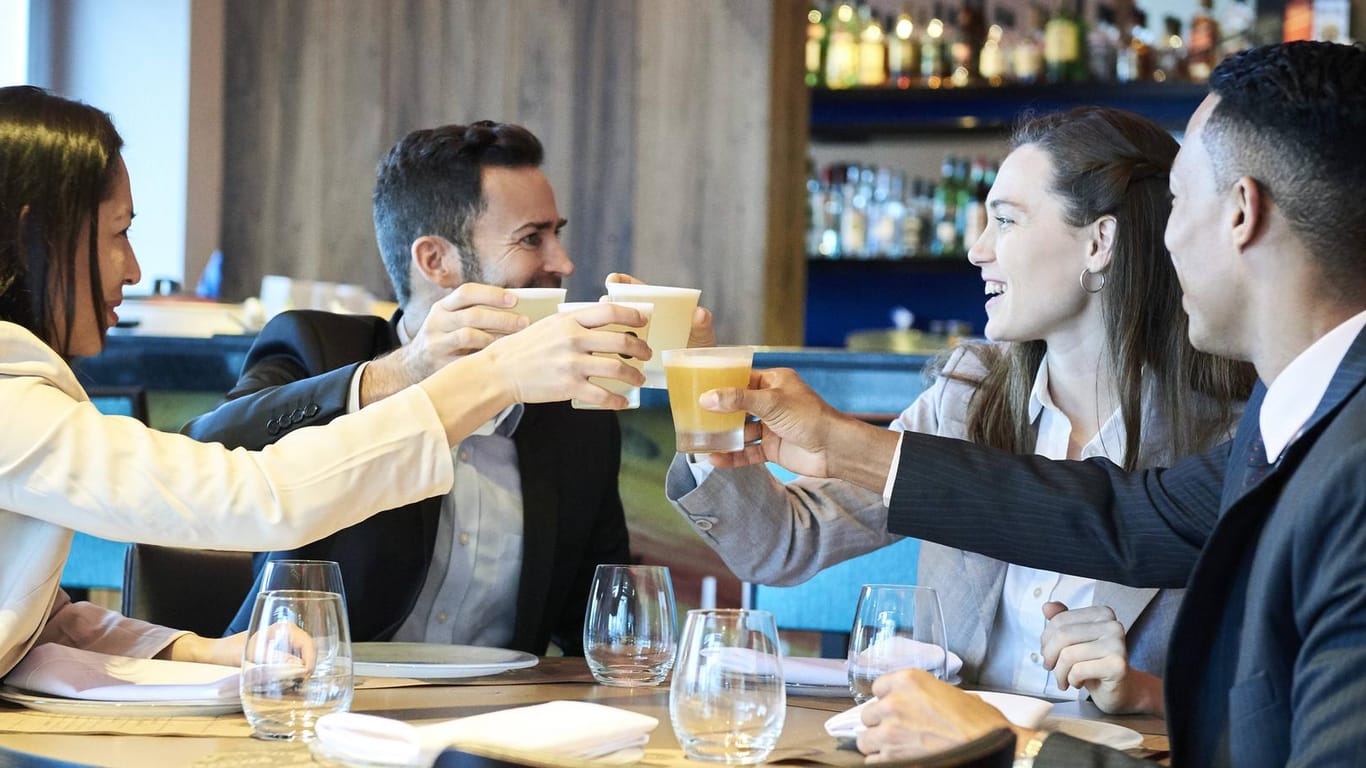 Eine Gruppe stößt in einer Bar mit Getränken an: Bei Social Match-Events in München kann man super neue Leute kennenlernen.