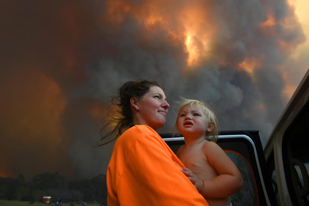 Eine Australierin und ihre 18 Monate alte Tochter vor den Flammen: Die Brände in Australien verschlimmern sich immer weiter.
