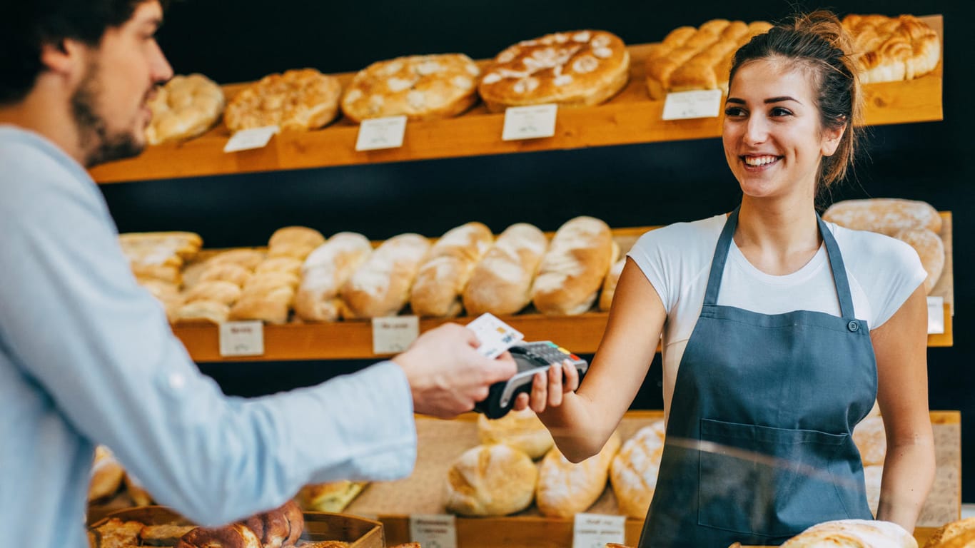 Kunde zahlt mit Karte in einer Bäckerei: Unternehmen mit elektronischen Kassensystemen sind ab 2020 verpflichtet, Kassenzettel auszudrucken.