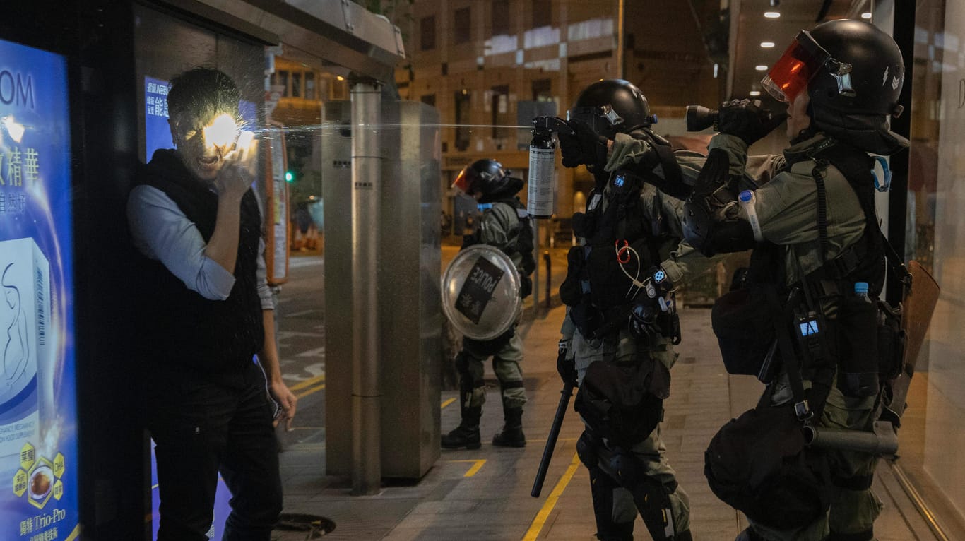 Ein Polizist spritzt Pfefferspray in das Gesicht eines Mannes in Hongkong: Die Gewalt hat sich mittlerweile auf die Universitäten ausgeweitet.