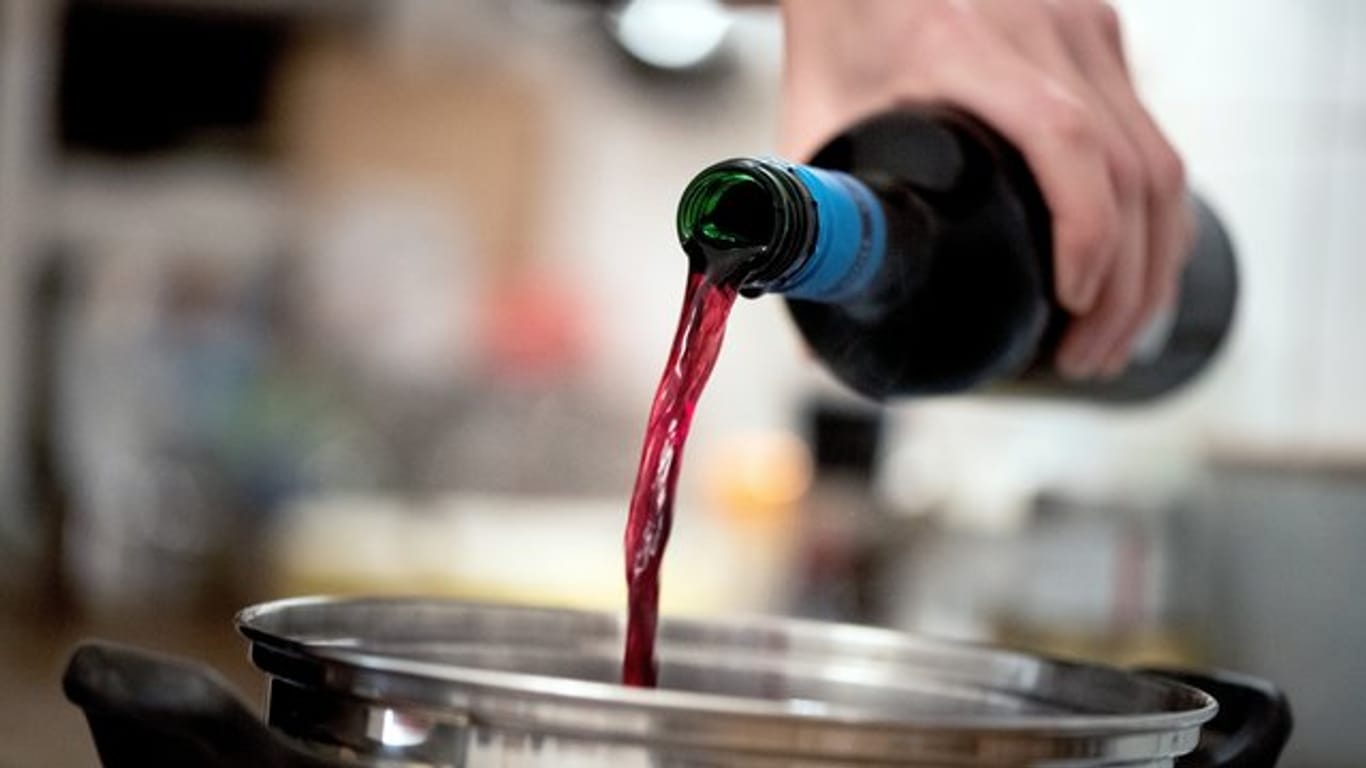 Mann kocht mit Rotwein: Theoretisch verdampft Alkohol beim Kochen – wie lang das dauert und ob wirklich alles verdampft, ist aber unklar.