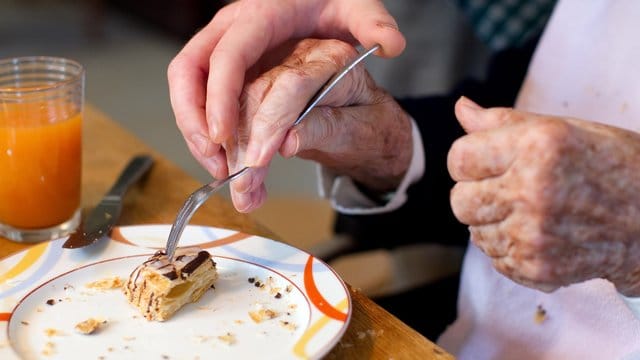 Ein junger Mann, der ein Freiwilliges Soziales Jahr (FSJ) absolviert, hilft einer Bewohnerin in einer Wohngemeinschaft für Demenzkranke. Ein junger Mann, der ein Freiwilliges Soziales Jahr (FSJ) absolviert, hilft einer Bewohnerin in einer Wohngemeinschaft für Demenzkranke.