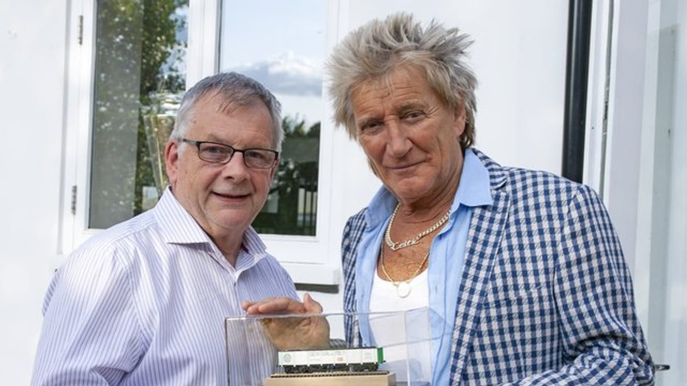 Rod Stewart (r), britischer Musiker, steht neben Steve Flint, Chefredakteur der britischen Fachzeitschrift "Railway Modeller", der ihm ein Geschenk, ein Modelleisenbahn-Waggon, überreicht.