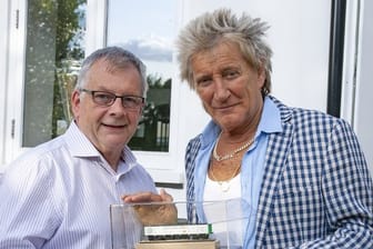 Rod Stewart (r), britischer Musiker, steht neben Steve Flint, Chefredakteur der britischen Fachzeitschrift "Railway Modeller", der ihm ein Geschenk, ein Modelleisenbahn-Waggon, überreicht.