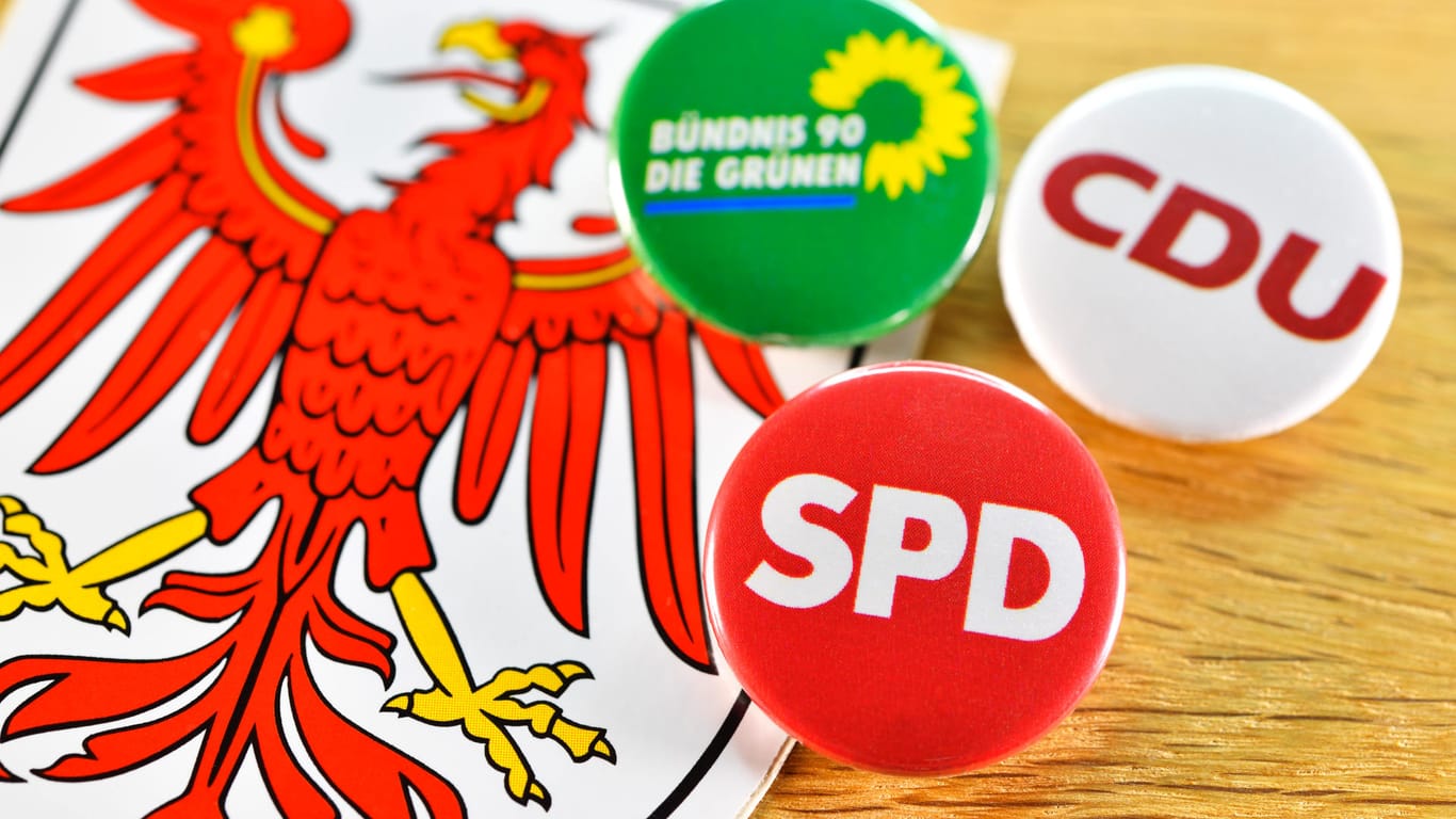 Landeswappen von Brandenburg und Anstecker von SPD, CDU und den Grünen: Die Landes-CDU hat dem Kenia-Koalitionsvertrag zugestimmt. Jetzt fehlen nur noch die SPD und die Grünen.
