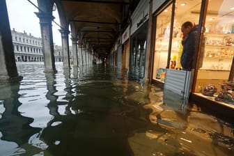 Ein Ladenbesitzer schaut aus seinem Geschäft auf den überfluteten Markusplatz.