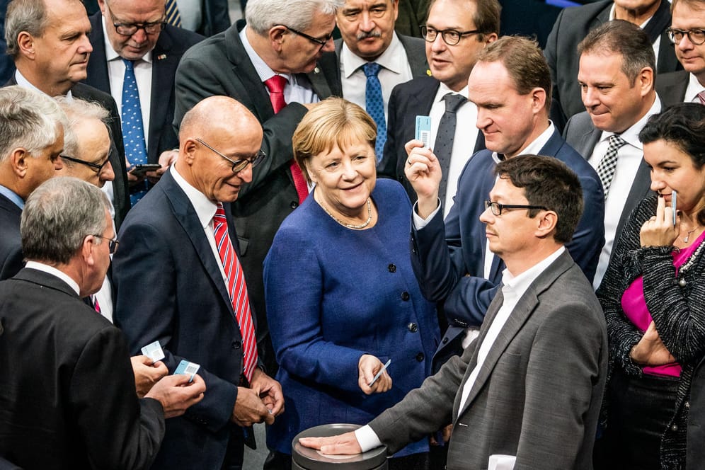 Bundeskanzlerin Angela Merkel (CDU) wirft bei der namentlichen Abstimmung zum Solidaritätszuschlag ihre Stimmkarte ein.