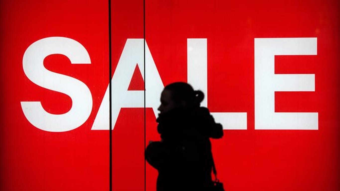 Eine Frau vor einem "Sale"-Werbeplakat: Outlet-Center liegen voll im Trend und locken immer mehr Schnäppchenjäger an.