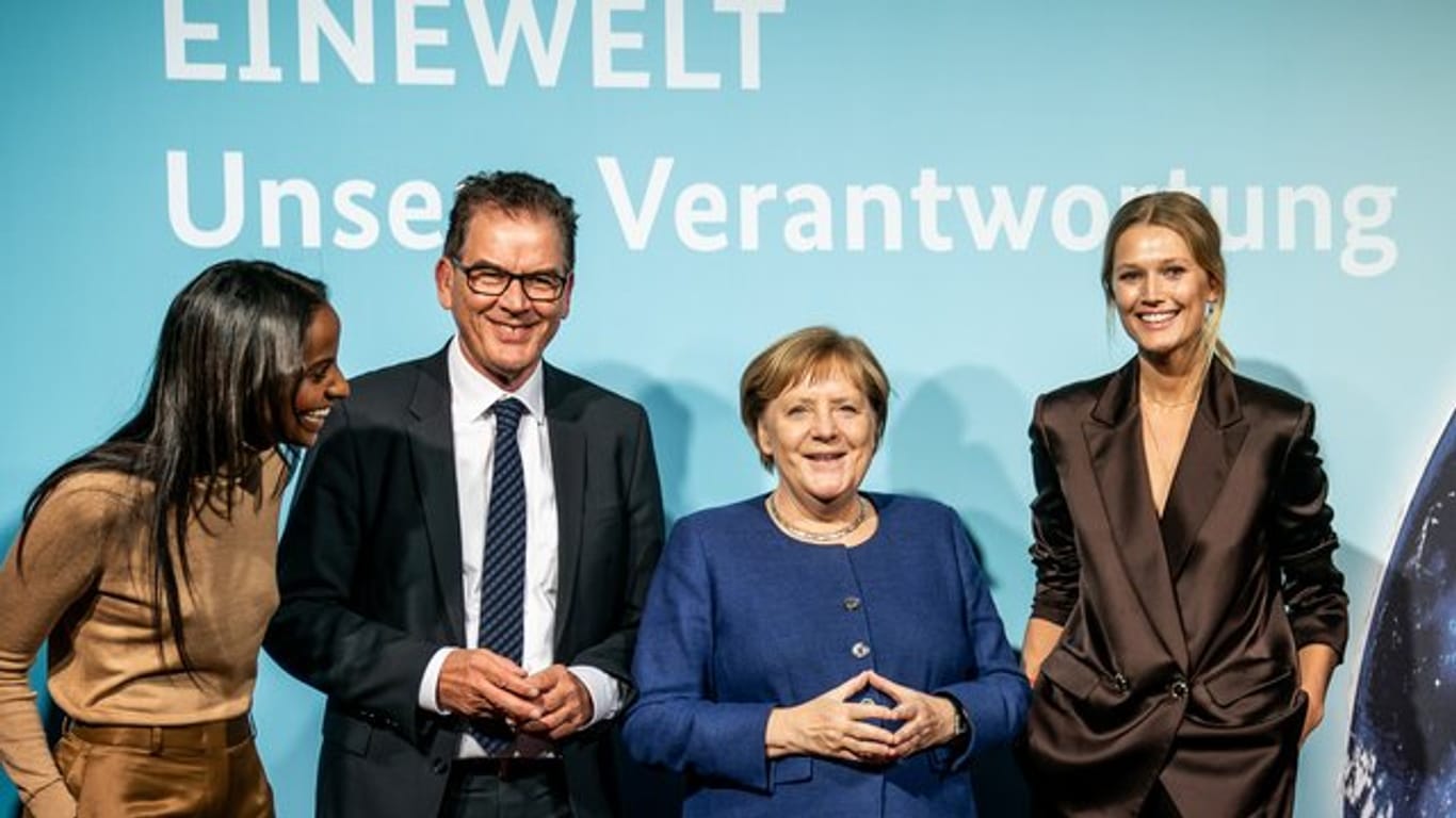 Bundeskanzlerin Angela Merkel und Entwicklungsminister Gerd Müller stehen zusammen mit den Ministeriums-Botschafterinnen Sara Nuru (l) und Toni Garrn (r) bei der Veranstaltung "Eine Welt - Unsere Verantwortung".