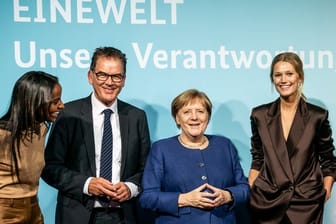 Bundeskanzlerin Angela Merkel und Entwicklungsminister Gerd Müller stehen zusammen mit den Ministeriums-Botschafterinnen Sara Nuru (l) und Toni Garrn (r) bei der Veranstaltung "Eine Welt - Unsere Verantwortung".