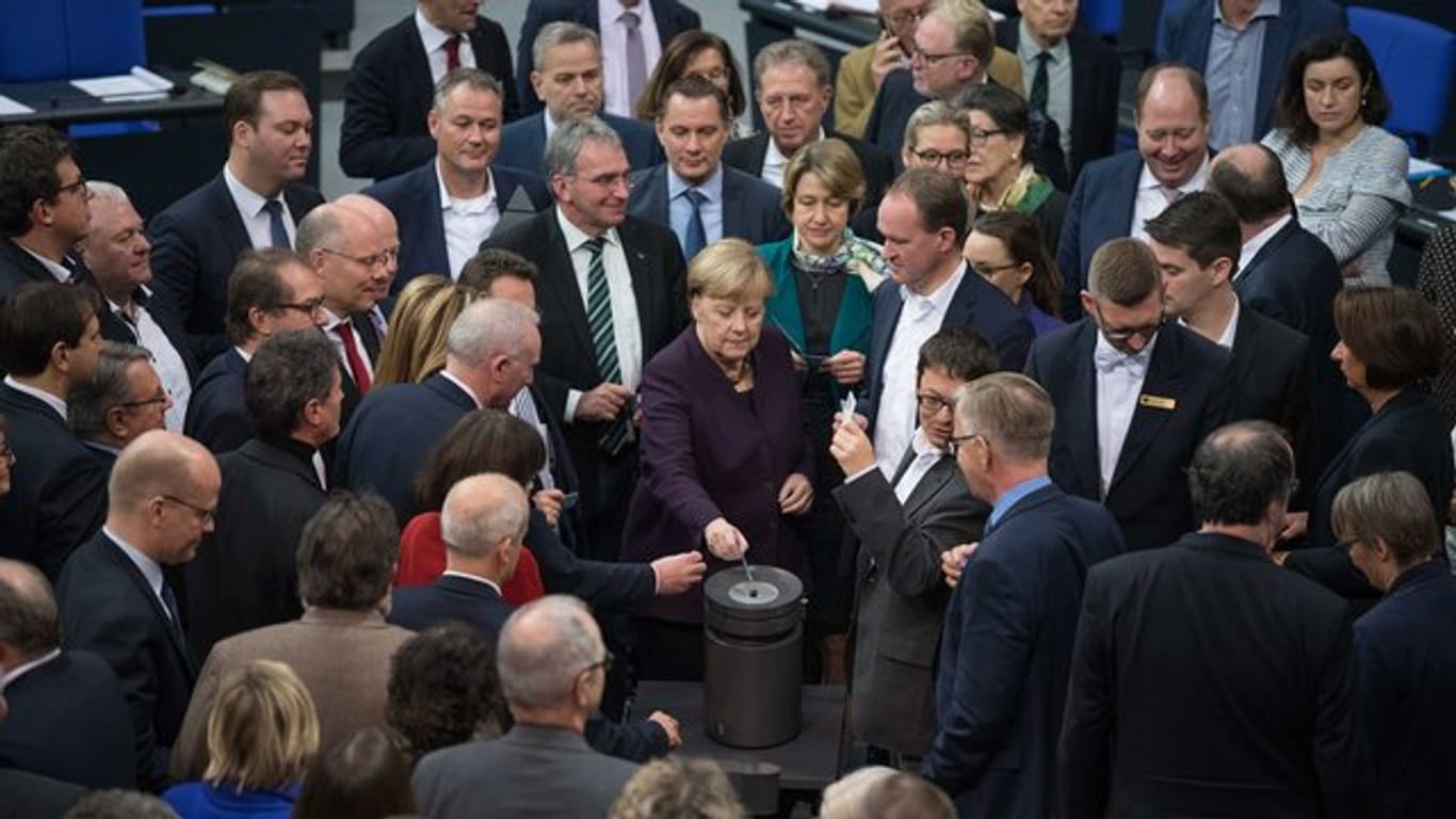 Bundeskanzlerin Angela Merkel (CDU) und weitere Abgeordnete stimmen bei der 128.