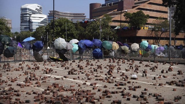Auf einer Straße vor einer Barrikade, die von Demonstranten der Polytechnischen Universität Hongkong gebaut wurde, sind Ziegelsteine verstreut. Auf einer Straße vor einer Barrikade, die von Demonstranten der Polytechnischen Universität Hongkong gebaut wurde, sind Ziegelsteine verstreut.
