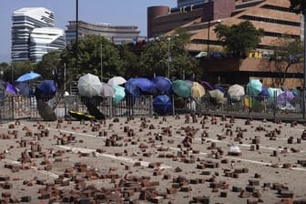 Auf einer Straße vor einer Barrikade, die von Demonstranten der Polytechnischen Universität Hongkong gebaut wurde, sind Ziegelsteine verstreut.