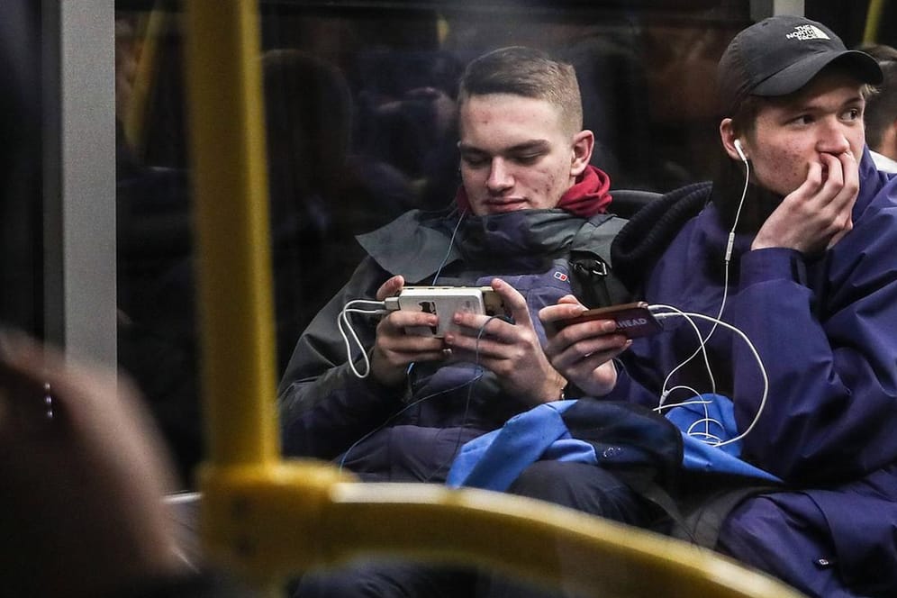 Junge Männer surfen in einem Bus (Symbolbild): Deutschland hat mit die teuersten Datentarife in Europa.