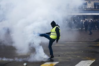 Ein Demonstrant tritt einen Tränengasbehälter von sich weg.
