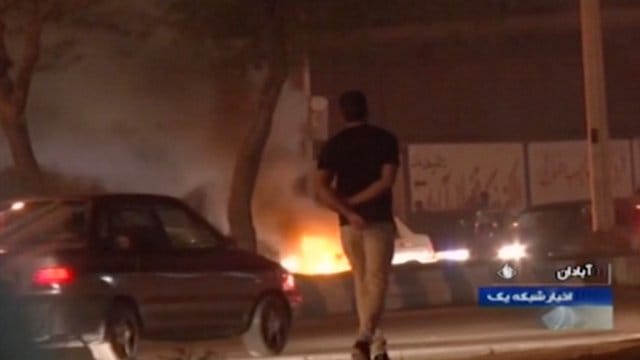 Das Videostandbild, das die staatliche Rundfunkgesellschaft der Islamischen Republik Iran zur Verfügung gestellt hat, geht ein Mann an einem Feuer vorbei, das von Demonstranten in Abadan gelegt wurde. Das Videostandbild, das die staatliche Rundfunkgesellschaft der Islamischen Republik Iran zur Verfügung gestellt hat, geht ein Mann an einem Feuer vorbei, das von Demonstranten in Abadan gelegt wurde.