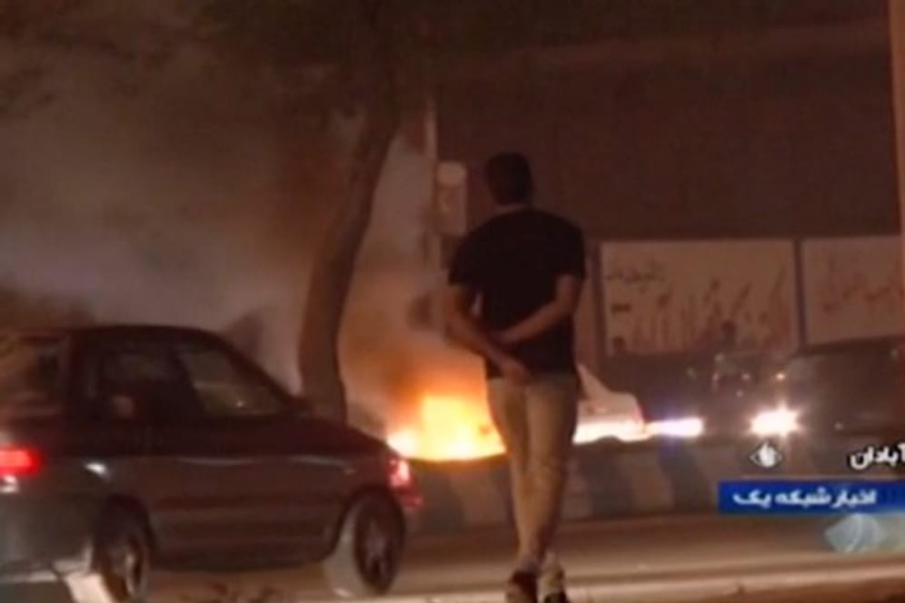 Das Videostandbild, das die staatliche Rundfunkgesellschaft der Islamischen Republik Iran zur Verfügung gestellt hat, geht ein Mann an einem Feuer vorbei, das von Demonstranten in Abadan gelegt wurde.
